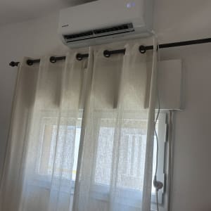 מזגן מותקן מעל חלון עם וילון לבן