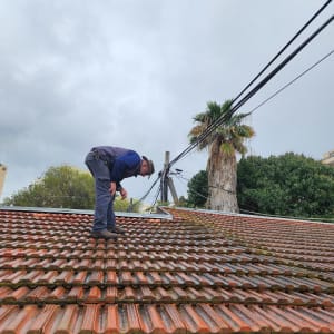 אדם עומד על גג רעפים אדום ובודק אותו