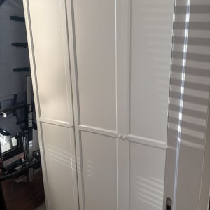 ארון לבן עם דלתות סגורות בחדר מואר.