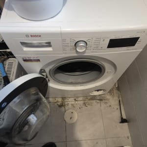 מכונת כביסה עם דלת פתוחה ודלי על המכסה