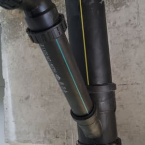 צינורות פלסטיק שחורים מחוברים לקיר בטון