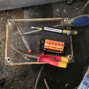 כלי עבודה חשמליים על רצפה, כולל מברג ומחבר חשמלי.