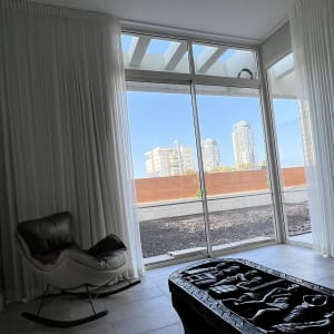 חלון זכוכית גדול עם נוף לעיר וכורסה בפנים החדר