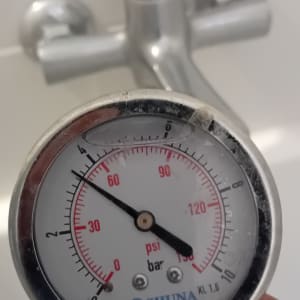 מד לחץ מים מוחזק ביד ליד ברז