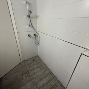 חדר מקלחת עם אריחים לבנים וראש מקלחת