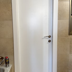 דלת לבנה עם ידית מתכת בחדר אמבטיה