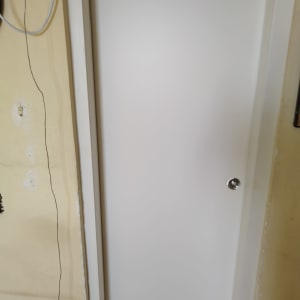 דלת לבנה עם ידית כסופה על קיר צהוב