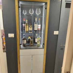 ארון תצוגה מעץ עם בקבוקי משקאות וכוסות