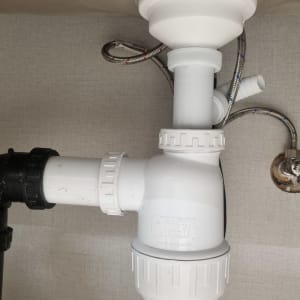 צנרת פלסטיק לבנה ושחורה מתחת לכיור