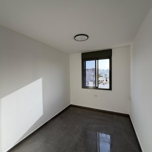 חדר ריק עם קירות צבועים ורצפת אריחים אפורה