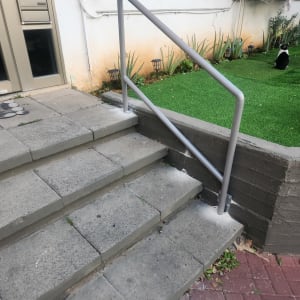 מעקה מתכת אפור ליד מדרגות בטון