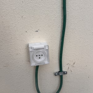 שקע חשמלי מותקן על קיר עם כבל ירוק