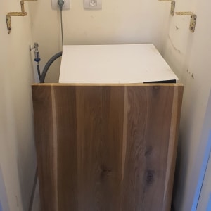 לוח עץ מונח על מכונת כביסה בחדר קטן