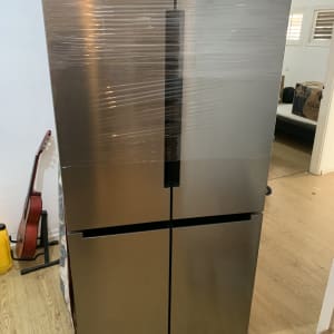 מקרר עטוף בניילון בחדר עם גיטרה וקרטון