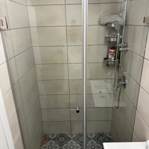 מקלחון עם דלת זכוכית ומקלחת גשם
