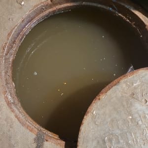 פתח ביוב עם מכסה פתוח ומים עכורים