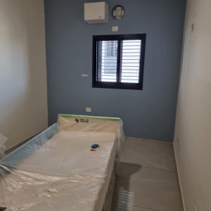 חדר עם קיר צבוע בכחול ומיטה מכוסה בניילון