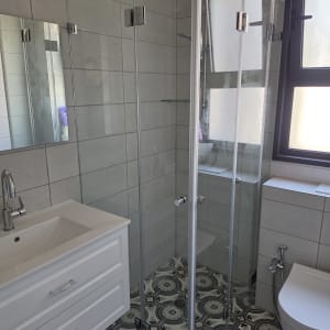 מקלחון זכוכית בחדר אמבטיה מודרני עם אריחים מעוצבים