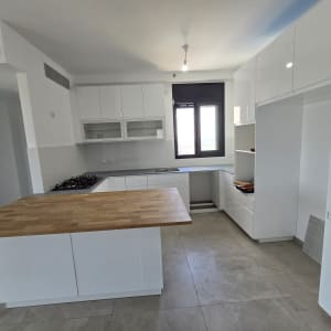 מטבח חדש עם ארונות לבנים ומשטח עץ