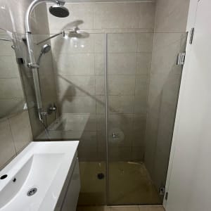 מקלחת עם ראש גשם ודלת זכוכית שקופה