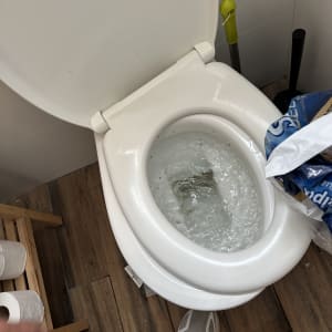 אסלה פתוחה עם מים זורמים, מברשת שירותים בצד