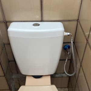 אסלה עם מיכל הדחה וצינור מים מחובר