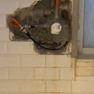 צינורות חשופים בקיר עם חור