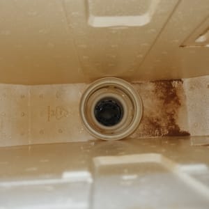 תא שירותים עם כתמי חלודה ופתח ניקוז