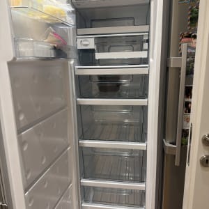 מקרר פתוח עם מדפים ריקים ומעט פריטים בדלת