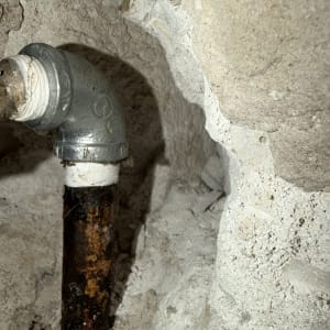 חשיפה ותיקון של צינור מים בתוך פתח בקיר בטון