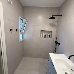 חדר אמבטיה משופץ עם מקלחת וכיור חדשים