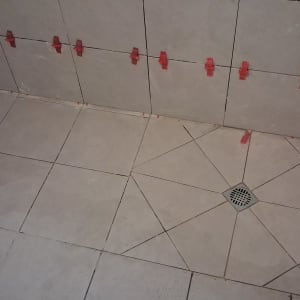 אריחים מותקנים עם תפסנים אדומים בחדר אמבטיה