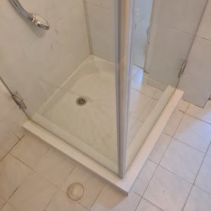 מקלחון עם אריחים לבנים וראש מקלחת