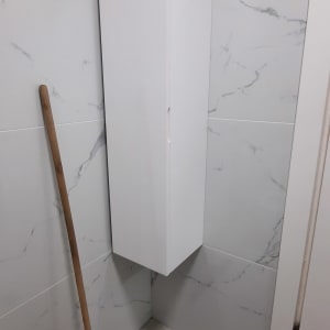 מגב סגול עם ידית עץ ליד ארון לבן