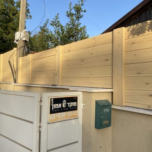 גדר עץ חדשה מותקנת על קיר בטון