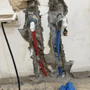 התקנת צנרת מים חמים וקרים בתוך קיר חצוב במהלך עבודת אינסטלציה