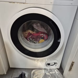 מכונת כביסה עם מגש אלומיניום וגרב על הרצפה