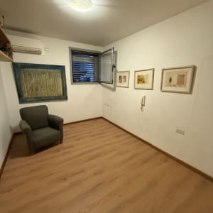 חדר עם רצפת פרקט, כורסה ותמונות על הקיר