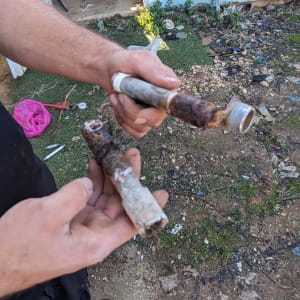 ידיים מחזיקות צינורות חלודים בעבודת אינסטלציה