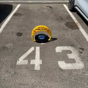 מחסום חניה צהוב עם כיתוב בעברית