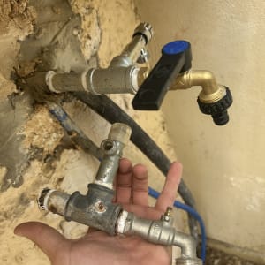 ברזים וצינורות מחוברים לקיר עם יד אוחזת