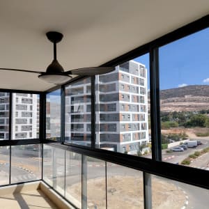 חלונות אלומיניום במרפסת עם נוף לבניינים והרים