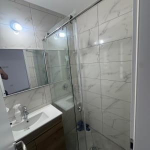 חדר אמבטיה עם מקלחון זכוכית וכיור