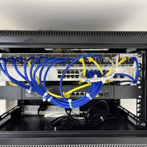 ארון תקשורת עם כבלים כחולים וצהובים מחוברים למתגים