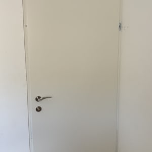 דלת פנים קו אפס בצבע בהיר עם ידית ניקל מותקנת בבית