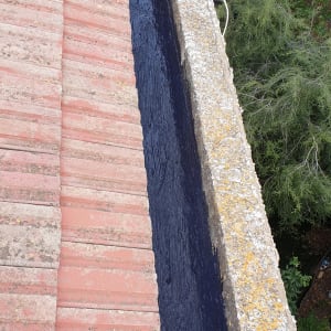 איטום גג עם חומר שחור בין רעפים לקיר בטון