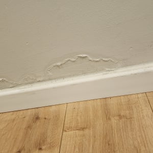 קיר עם סימני רטיבות מעל פנל עץ