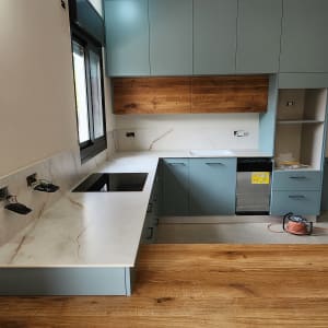 מטבח עם משטחי שיש לבנים וארונות כחולים