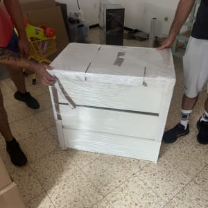 שני אנשים אורזים רהיט עטוף בניילון