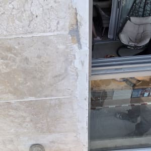 עבודת איטום ותיקון טיח בחזית בניין אבן בגובה